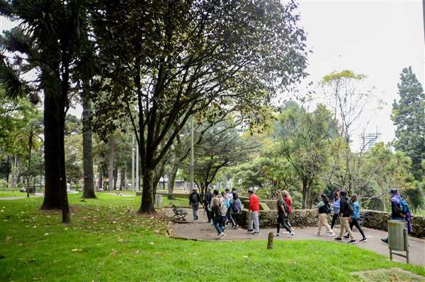 Personas caminando por un parque arbolado de Bogotá